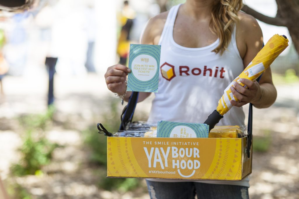 Female with Rohit tank top holding a tray filled with gifts.