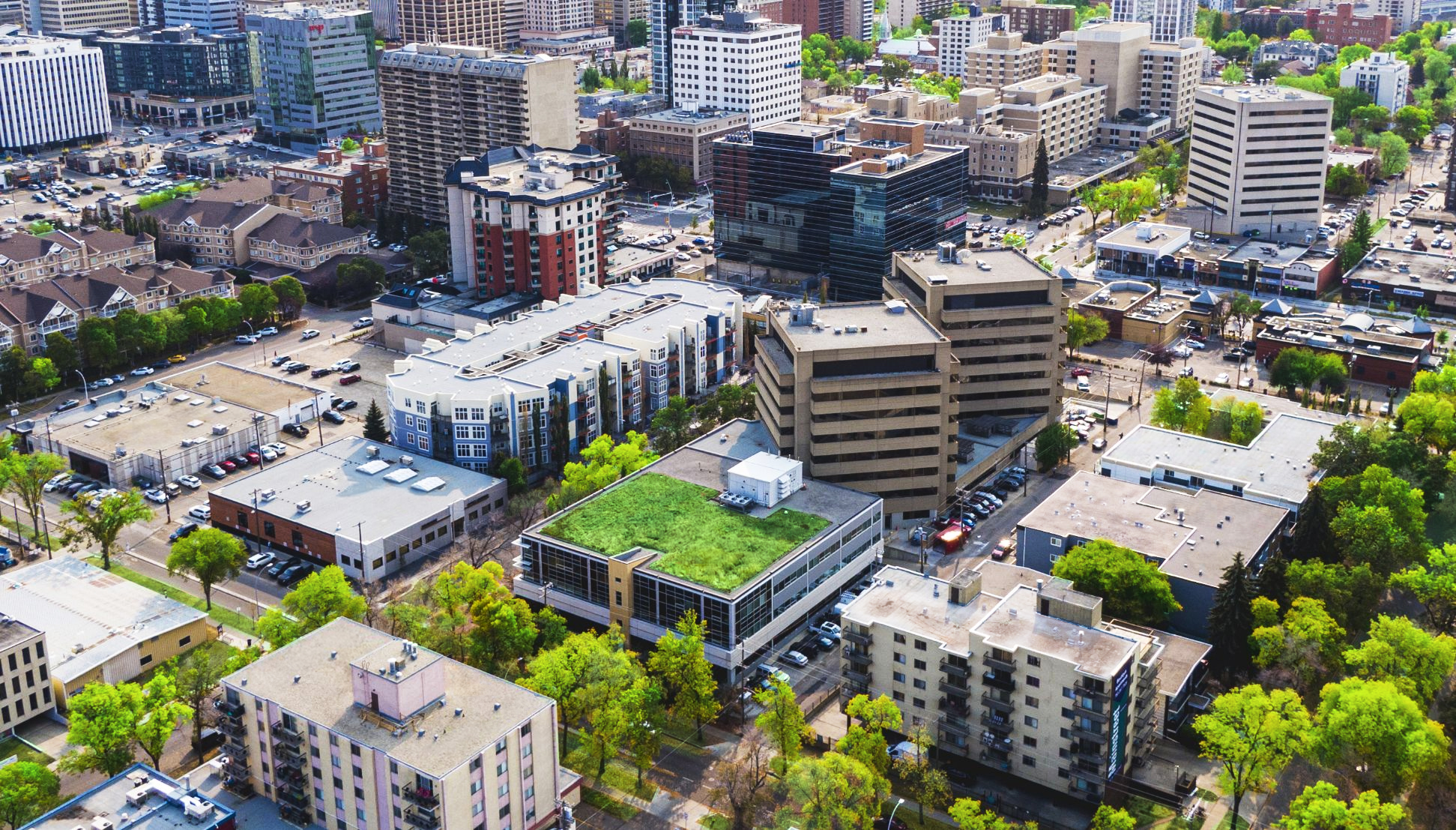 Aerial view of One Twelve Campus and many other buildings with lush green trees and grass around.